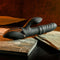 Black silicone rechargeable vibrator with clitoral stimulator on textured stone surface.