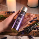 Anoint Perfumery Lavender Flower & Vanilla Bean massage oil bottle held in hand, surrounded by lavender and vanilla pods.