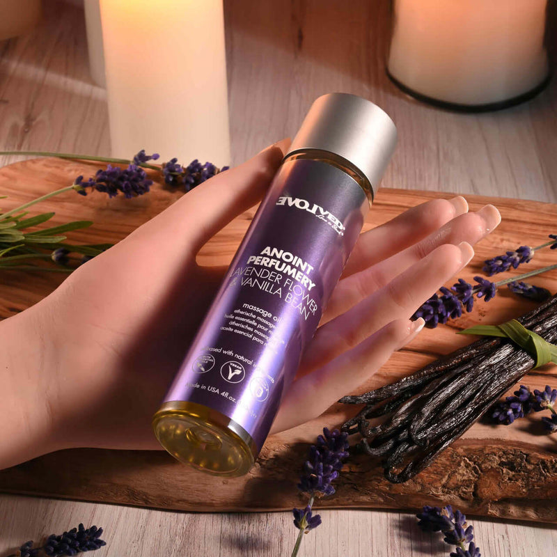 Anoint Perfumery Lavender Flower & Vanilla Bean massage oil bottle held in hand, surrounded by lavender and vanilla pods.