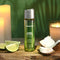 Anoint Perfumery Lime Infused Coconut Massage Oil bottle surrounded by lime, coconut, and candles.