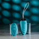 Evolved Oval Office Remote Control Vibrating Egg in turquoise placed on a glass platform with remote control adjacent