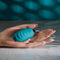 Hand holding Evolved Oval Office remote control vibrating egg in blue.