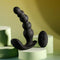 Rechargeable black silicone vibrating anal beads with remote control on pastel geometric surfaces.