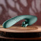 Poseable teal thrusting vibrator with rotating stimulator prongs on wooden surface.