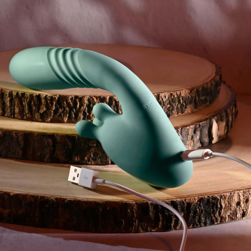 Poseable thrusting vibrator with rotating prongs on wooden display, featuring USB charging cable for convenience.
