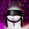 Adjustable black harness for strap-on use, showcasing a smooth, curvy design against a pink dotted background.