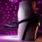 Curved silicone triple vibrator in a harness, showcased against vibrant disco lights for pleasure and excitement.