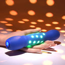 Disco Diva Rechargeable Silicone Vibrator Blue glowing with LED lights in hand on a colorful background.