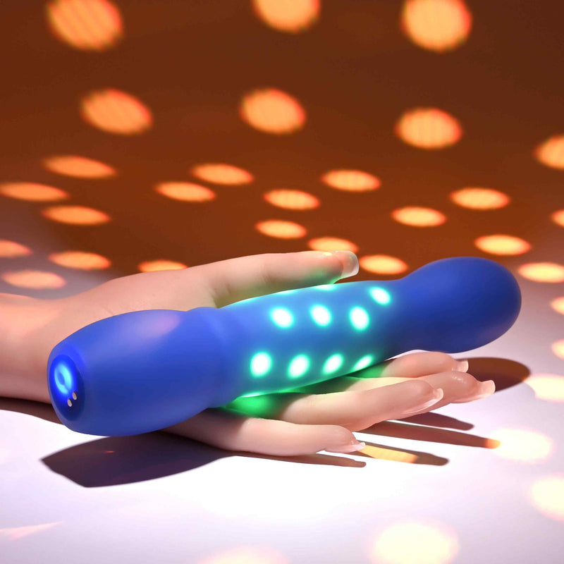 Disco Diva Rechargeable Silicone Vibrator Blue glowing with LED lights in hand on a colorful background.
