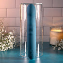 Queen of All Trades blue silicone dual vibrator displayed in a glass container surrounded by candles and flowers.