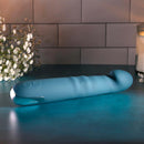 Rechargeable blue silicone dual vibrator on a table with flowers, designed for intense pleasure and satisfaction.