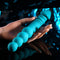 Hand holding a blue silicone dual-ended vibrator with textured shaft and pleasure beads, showcasing its flexible design.