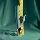 The Shimmy Vibrator with Clitoral Stimulator Green next to a ruler for size comparison on a soft green background.