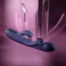 Bow Down Vibrator with Clitoral Stimulator Purple lying on soft pink background with clear geometric shapes.