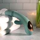 Evolved Rub Me Tender G-spot Clitoral Stimulator in mint green resting on towels with candles in the background.