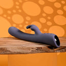 Poppin Good Time Rechargeable Rabbit Vibrator Purple on a wooden surface with an orange dotted background.