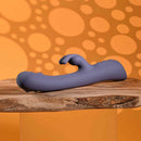 Poppin Good Time Rechargeable Rabbit Vibrator Purple on a wooden surface against an orange dotted background.