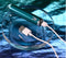 Playboy Emerald petite glass tip vibrator charging with USB cable on a metallic blue background