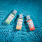Gender X Flavored Lube Travel 3-Pack with Spa Day, Tropical Passion, and Beach Bliss bottles on water surface.