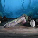 Gender X Monsters Ball Thrusting Vibrating Dildo with Remote Control on a wooden surface with ocean background.