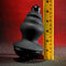 Gender X Echo Vibrator with detachable silicone sleeve next to a tape measure on a textured red and gray background.