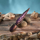 Gender X Into the Deep Silicone Vibrating Dildo Purple on a wooden surface with seashells.