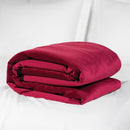 Liberator Fascinator Travel Throw Velvish Merlot folded on a bed, perfect for intimate moments.