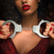 Stylish woman holding Temptasia Beginner Cuffs in silver, showcasing comfortable BDSM handcuffs with adjustable design and safety release lever.