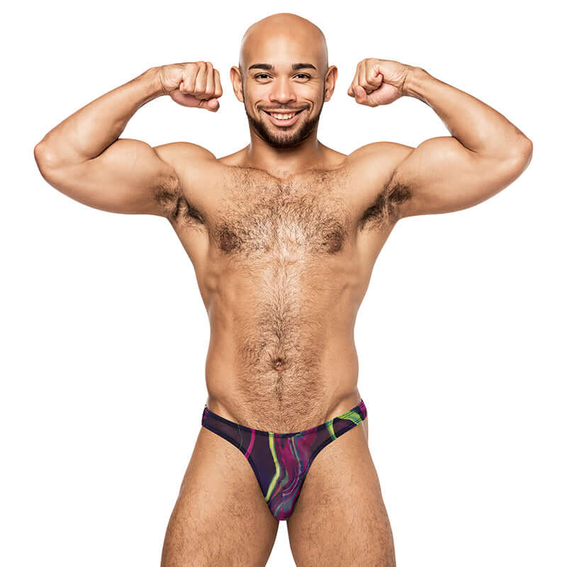 Muscular man flexing while wearing the Galactic Print Bong Thong from Male Power Lingerie, showcasing its vibrant colors.