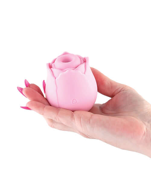 Hand holding a pink rechargeable rose-shaped clitoral stimulator made of body-safe silicone.