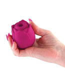 Hand holding a red silicone vibrating rose clitoral stimulator for intimate pleasure.