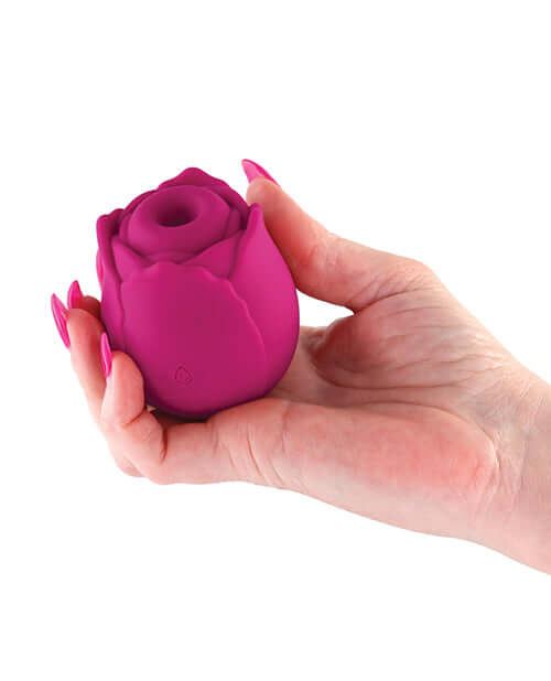 Hand holding a red silicone vibrating rose clitoral stimulator for intimate pleasure.