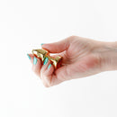 Rear Assets Aluminum Anal Plug Petite Gold Red held in a hand, showcasing its sleek design and metallic finish.