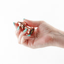 Rear Assets Aluminum Anal Plug Petite Rose Gold Rainbow held in a hand showcasing its elegant design and compact size.