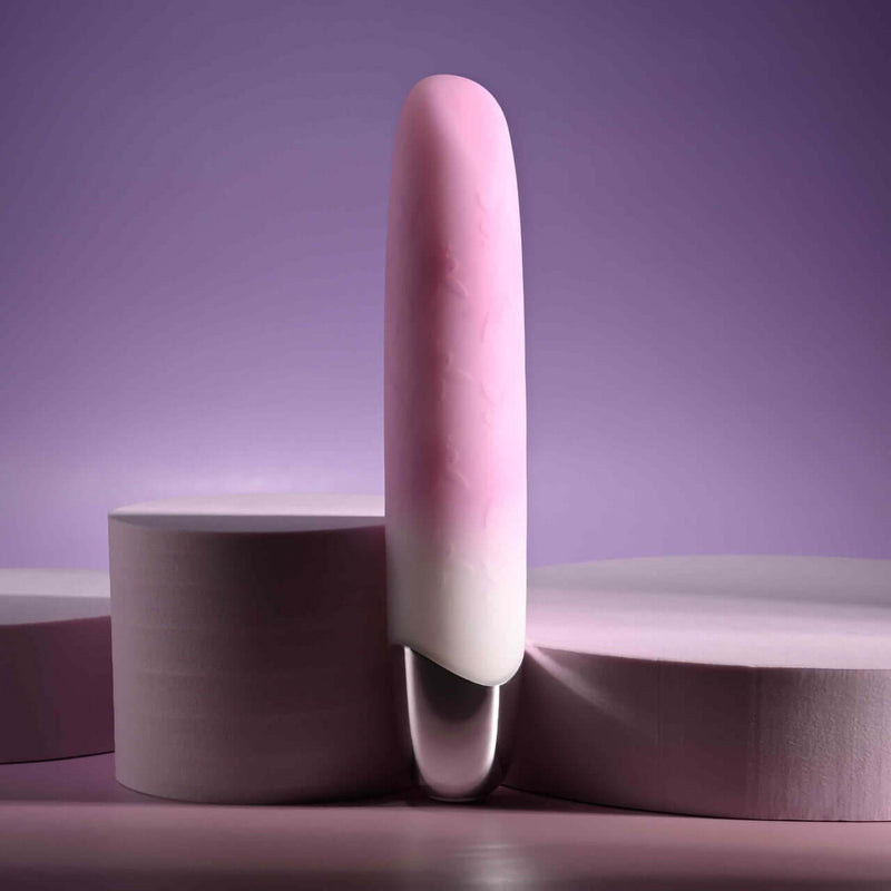 Playboy Bunnies on Parade pink rechargeable silicone vibrator on a purple background.