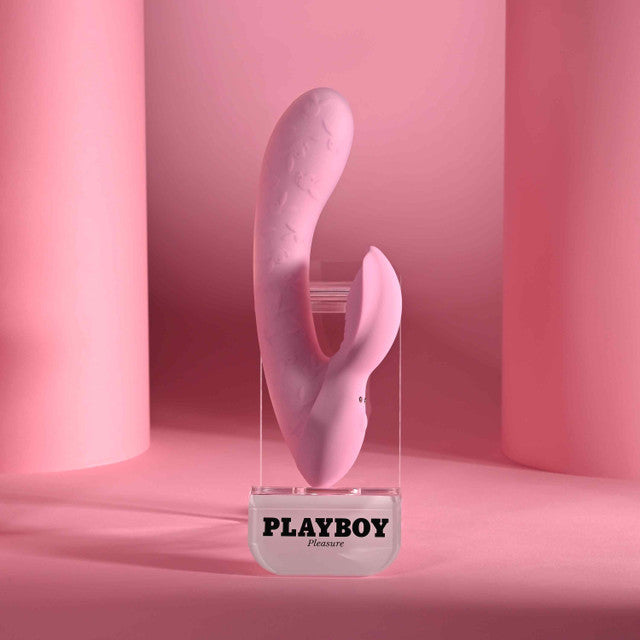 Playboy Rabbit Party Silicone Rabbit Vibrator Purple displayed on a clear pedestal with pink backdrop.