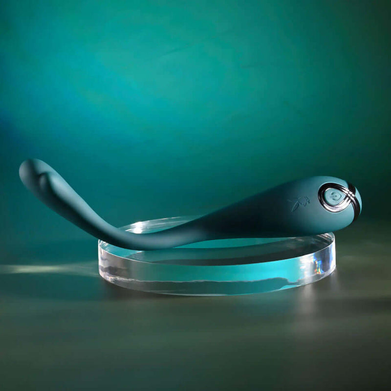 Playboy Pin Point Perfection Bendable Precision Vibrator displayed on a glass stand against a green background.