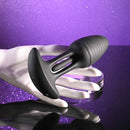 Playboy Rim Shot Rechargeable Silicone Anal Plug Black held in a hand against a sparkling purple background.