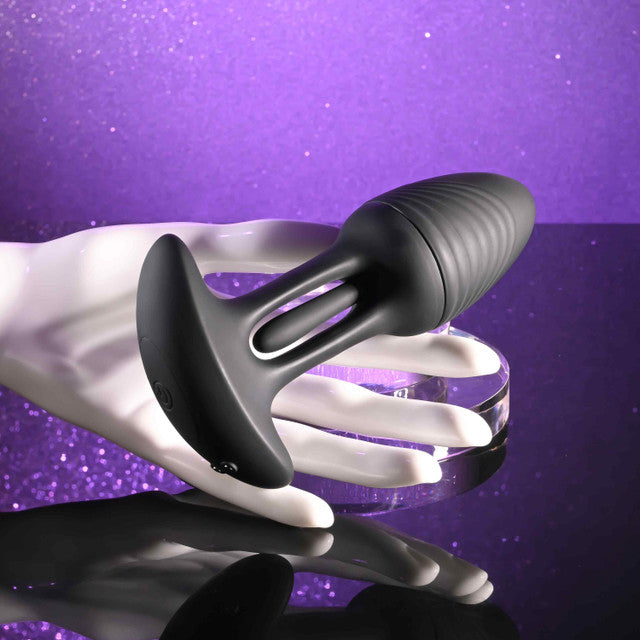 Playboy Rim Shot Rechargeable Silicone Anal Plug Black held in a hand against a sparkling purple background.