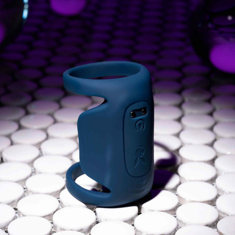 Playboy Jet Pack Double-Ring Penis Vibrator for Enhanced Pleasure in dark blue on a vibrant tile surface