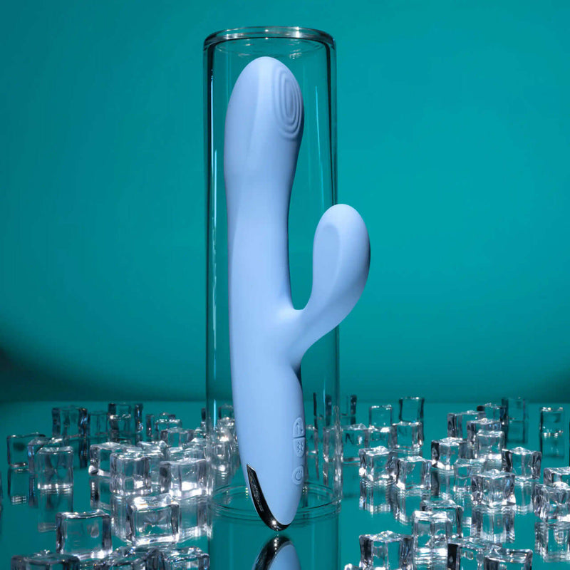 Playboy Up and Away Rechargeable Silicone Rabbit Vibrator in blue displayed in a glass container with ice cubes.