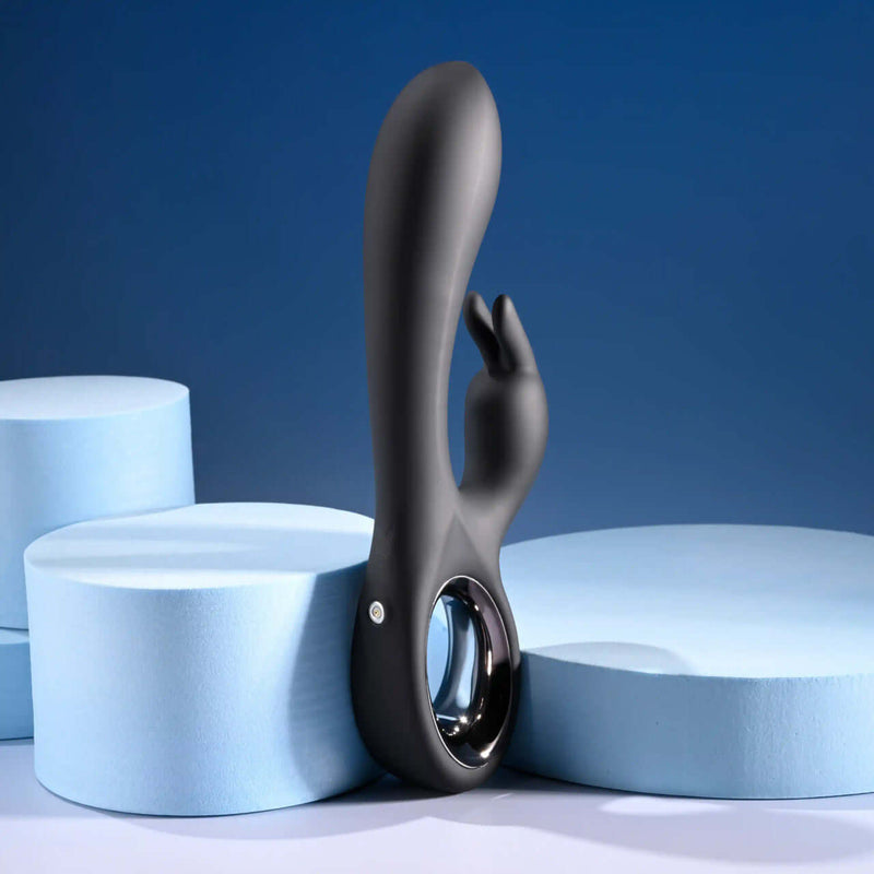 Black silicone dual vibrator with chrome handle, displayed on blue foam backgrounds, emphasizing its sleek design.