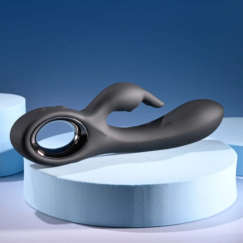 Playboy Late Night Bunny rechargeable silicone dual vibrator in sleek black on soft blue background.