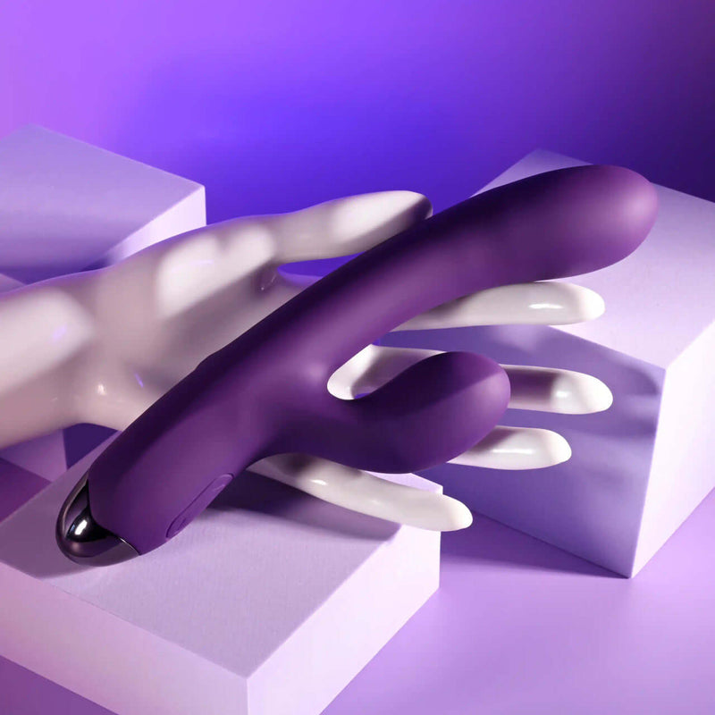 Playboy New Crush rechargeable dual vibrator in purple, featuring two flexible shafts and a sleek design on a hand.