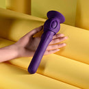 Playboy Wiggle It Rechargeable Wiggling Shaft Purple held in hand against a bright yellow background.