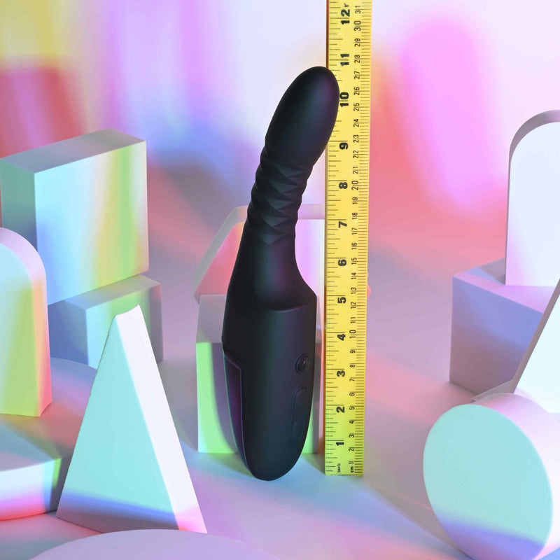 Playboy Overdrive Silicone Heating Vibrator Black next to a ruler on colorful geometric background.