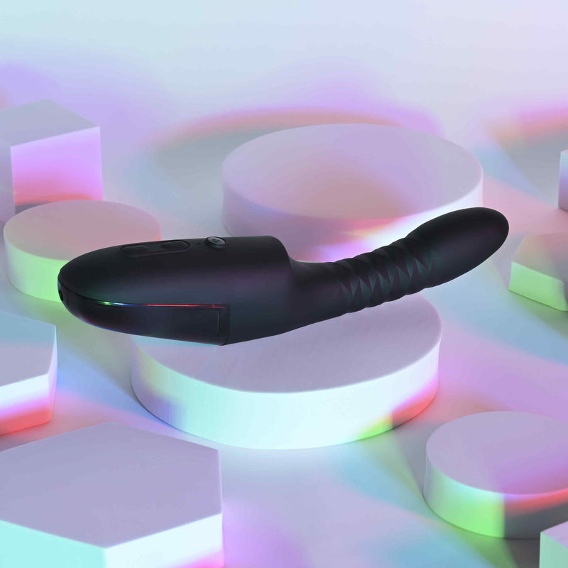 Playboy Overdrive Silicone Heating Vibrator Black on illuminated geometric shapes with vibrant reflections.