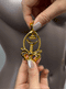 Woman holding gold Pulling Chain Nipple Clamps against a mannequin, showcasing its elegant design and details.