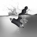 Petite Sensations Bubbles Black silicone vibrating anal plug submerged in water, showcasing its sleek design and functionality.