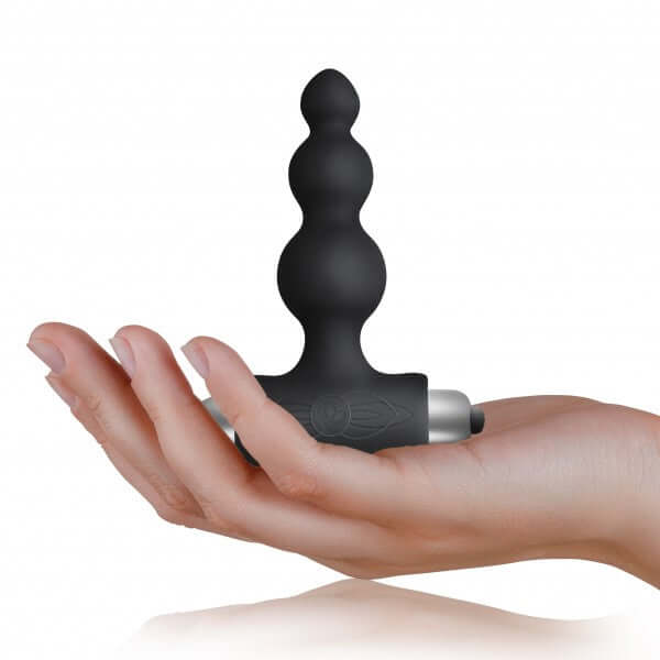 Petite Sensations Bubbles black silicone anal plug held in a hand, featuring a slim design and vibrant functions.